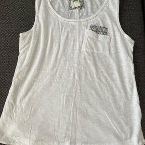 White Anthropologie tank top with flower detail, pocket, and cut out trim
